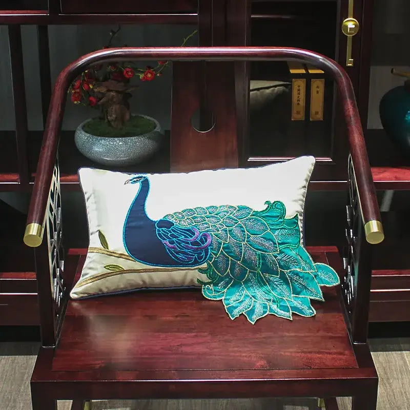 Rectangular cream satin cushion cover with an embroidered peacock design in teal and blue for living room decor