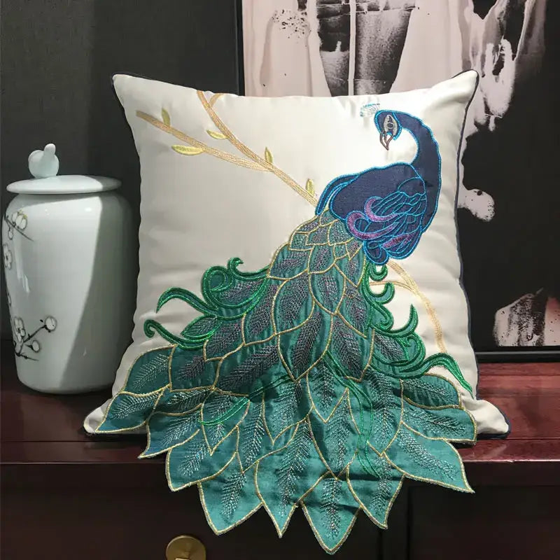 Cream satin cushion cover with embroidered peacock design in vibrant teal blue and gold for living room decor
