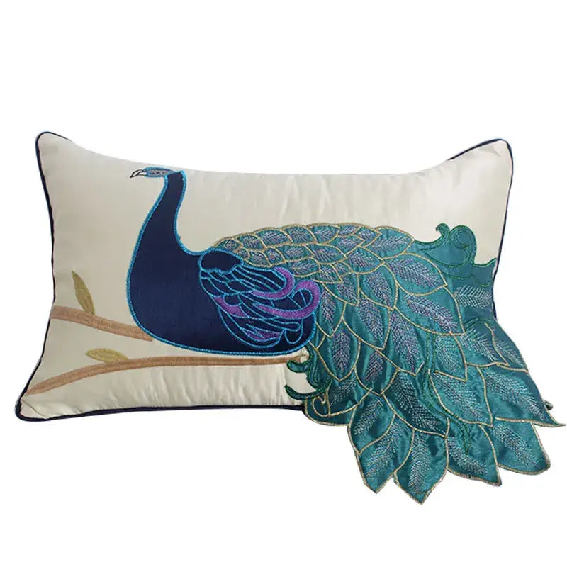Cream-colored satin cushion cover with an embroidered peacock design in navy blue teal purple and gold thread detailing
