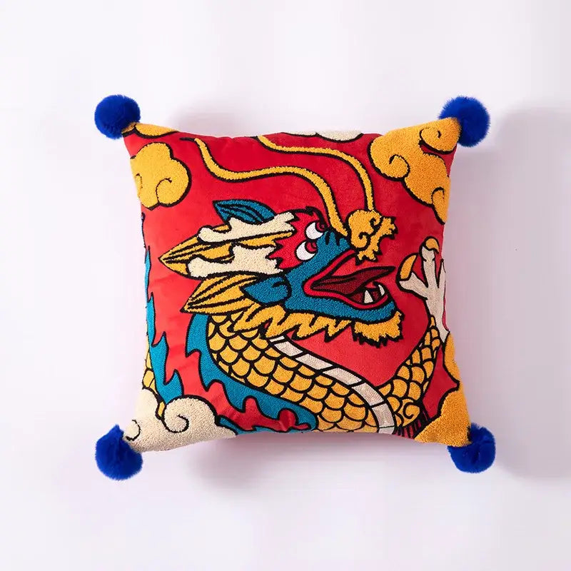 Vibrant red cushion cover with embroidered blue yellow and white dragon and fluffy blue pom-poms decorbites dragon year decor