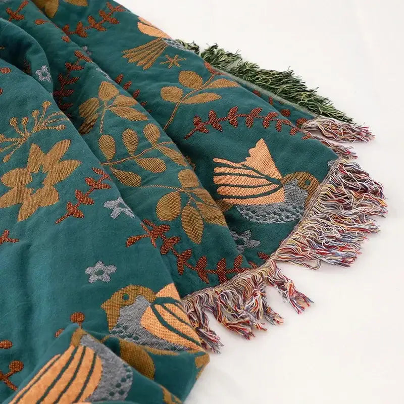 Embroidered teal and cream cotton sofa throw blanket with gold orange and gray bird and floral patterns and multicolored fringe