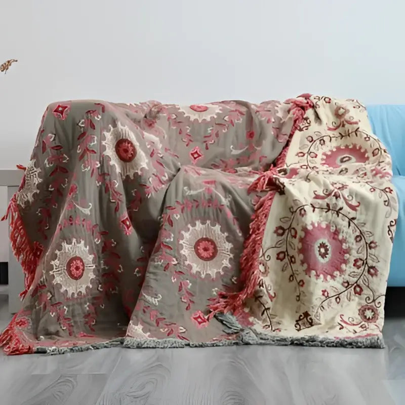 Embroidered teal and cream cotton sofa throw blanket with pink and cream floral embroidery on a muted gray background