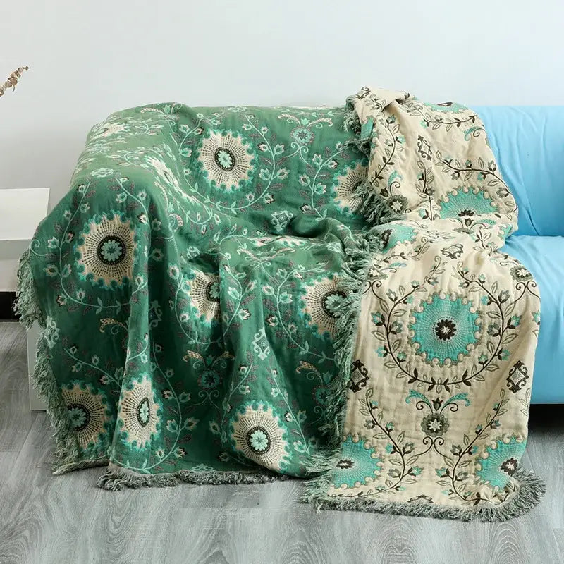 Cozy two-toned embroidered teal and cream cotton sofa throw blanket with floral patterns and fringed edges for living room