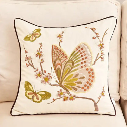 Cream-colored embroidered cushion cover with intricate butterfly and blossom designs in green brown and orange for sofa