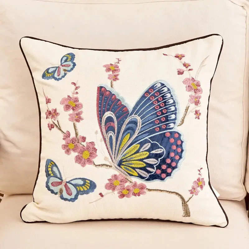 Cream-colored embroidered cushion cover with intricate butterflies and pink blossoms for living room sofa