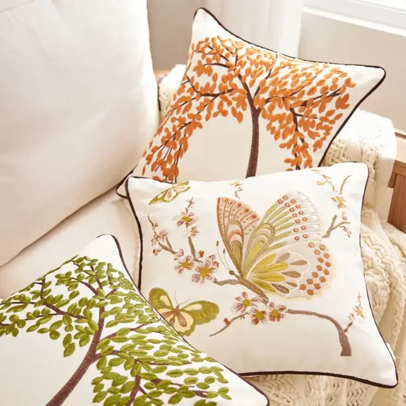 White embroidered cushion cover set with autumn tree and butterfly designs in orange green and brown for living room sofa
