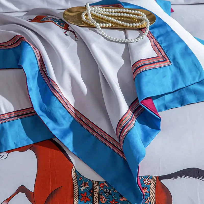 A luxurious white silk scarf with vibrant blue and red embroidered borders and a warm orange horse illustration for decorbites galloping horse bedding set