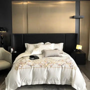 Embroidered white egyptian cotton bedding set featuring a satin duvet cover with floral embroidery and quilted black headboard