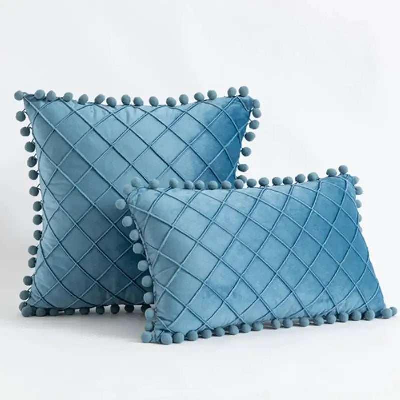 Blue velvet pillows with diamond-quilted pattern and decorative pom-poms complement decorbites corduroy striped pompom pillowcase