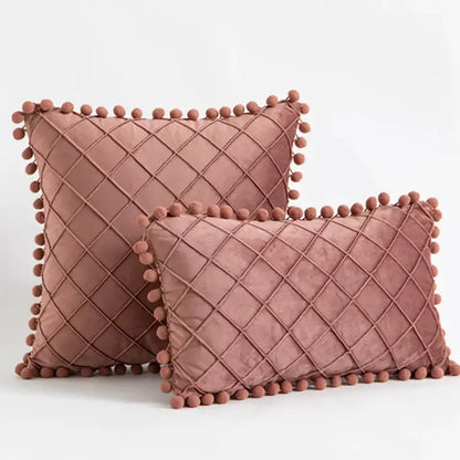 Two dusty rose velvet throw pillows with diamond-quilted pattern and pompom trim in decorbites corduroy striped style