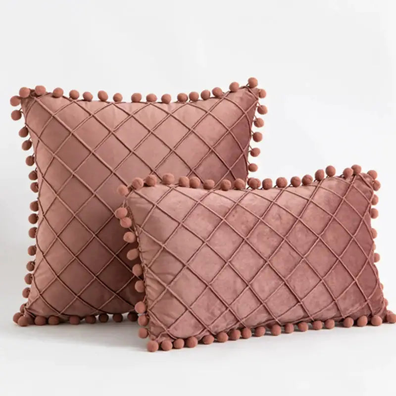 Two dusty rose velvet throw pillows with diamond-quilted pattern and pompom trim in decorbites corduroy striped style