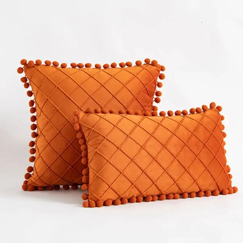 Orange velvet pillows with diamond-quilted pattern and pom-pom trim complement decorbites corduroy striped pompom pillowcase