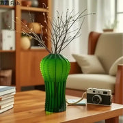 A translucent emerald green frosted glass cactus frosted vase with vertical ridges holding bare branches for living room decor