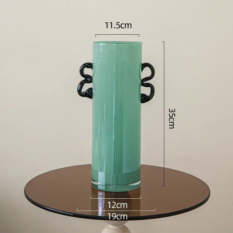 Emerald green glass vase featuring tall translucent teal glass with sleek black twisted handles for living room decor