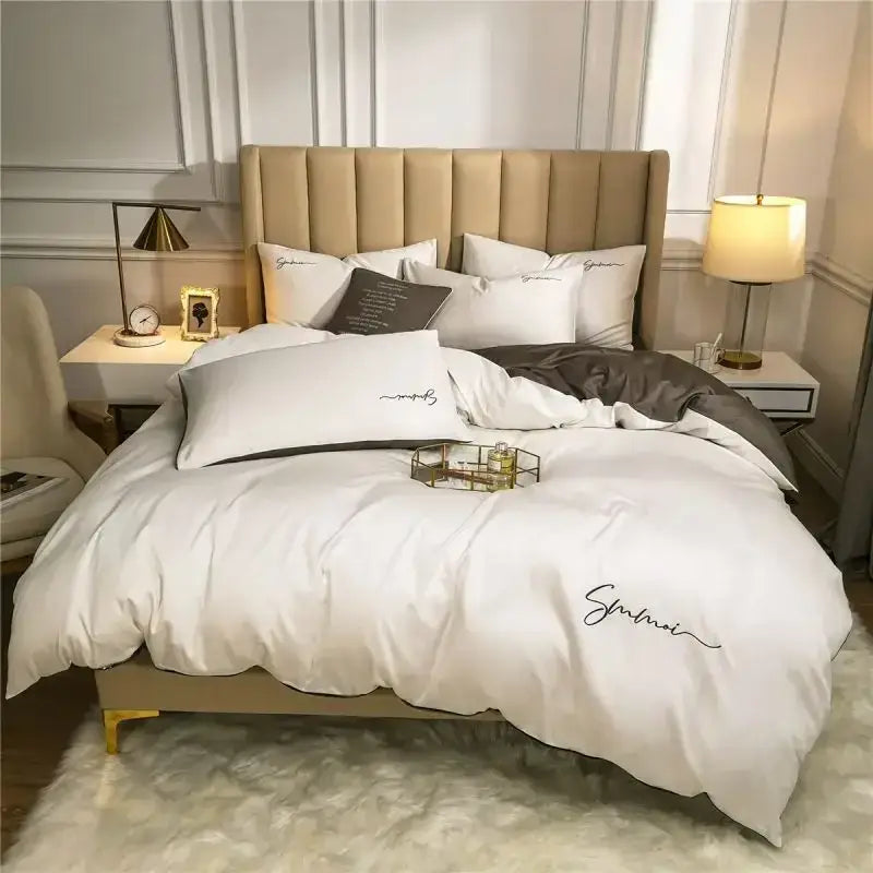 White satin duvet cover with black cursive embroidery and matching pillowcases in an egyptian cotton bedding set