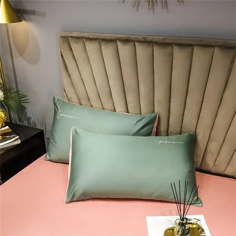 Pair of sage green satin pillowcases with delicate white embroidery in an egyptian cotton bedding set