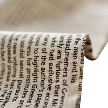 A close-up of an english newspaper style photography props kitchen placemat strip on textured off-white fabric background