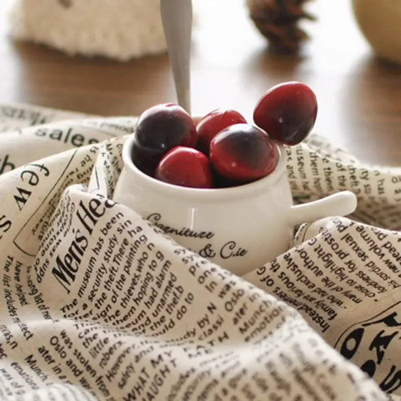 White ceramic cup with handle filled with glossy red and dark berries on english newspaper style photography props placemat