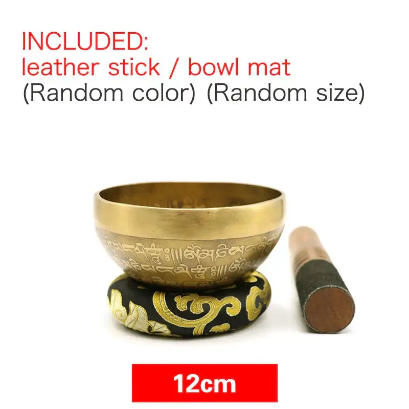 Engraved gold tibetan singing bowl with intricate script resting on a black and gold patterned cushion for meditation