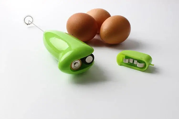 Bright green plastic electric mini mixer with whimsical face design and detachable whisk attachment for kitchen use