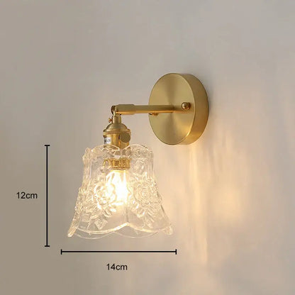 A delicate glass pendant light with intricate floral etchings mounted on a polished copper wall sconce for dining room