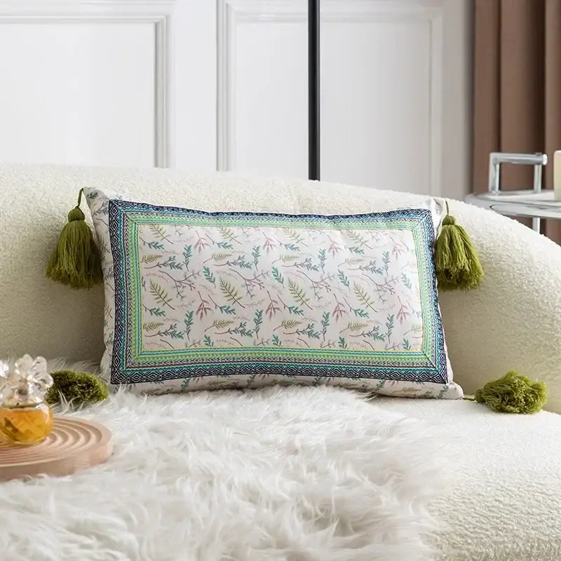 Square pillow cover set with white base, botanical prints in soft colors, teal navy geometric border, and olive tassels