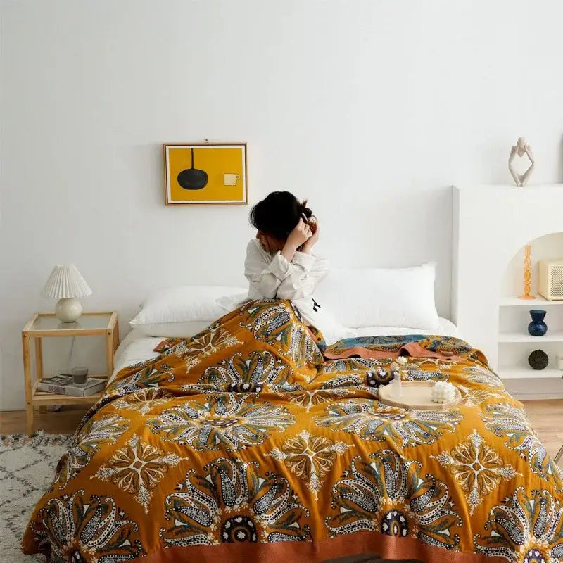 A vibrant mustard-yellow decorbites ethnic cotton blanket with brown cream and teal paisley floral patterns for bedroom decor