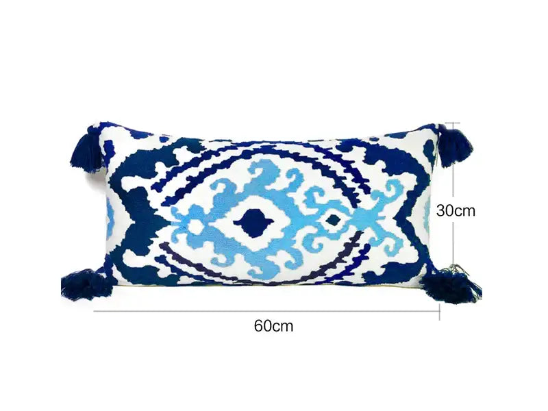 Rectangular pillow cover with white base, blue embroidered floral ikat patterns, and ethnic tassels for living room decor