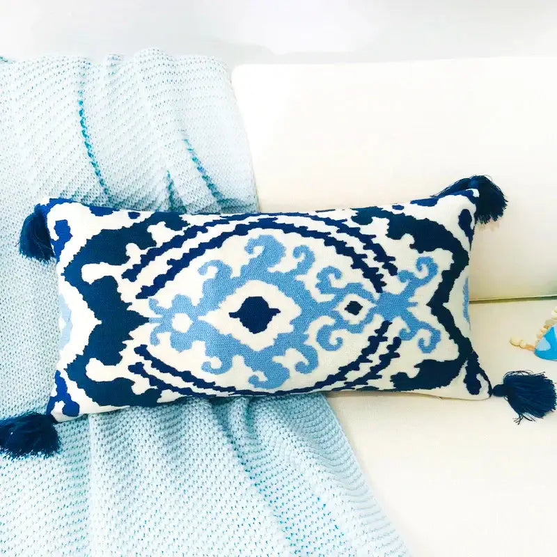 Rectangular pillow cover with navy blue and light blue embroidered floral ikat pattern and ethnic tassels on white fabric