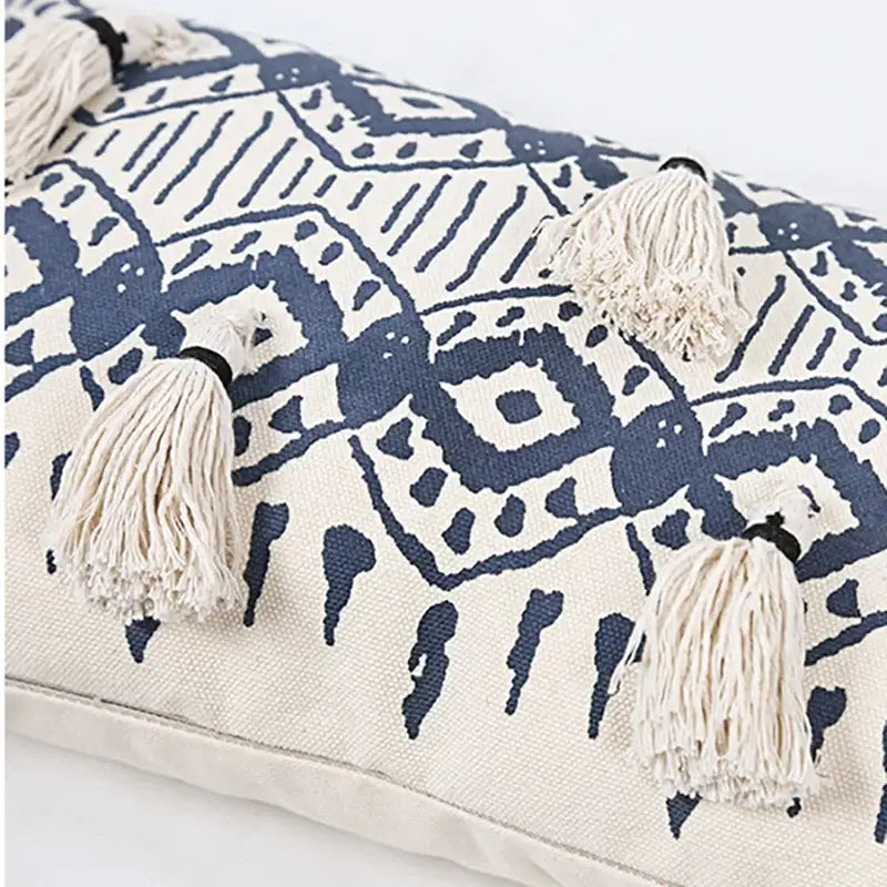Cream-colored cushion cover with navy blue ethnic geometric printed pattern and cream tassels for living room decorbites