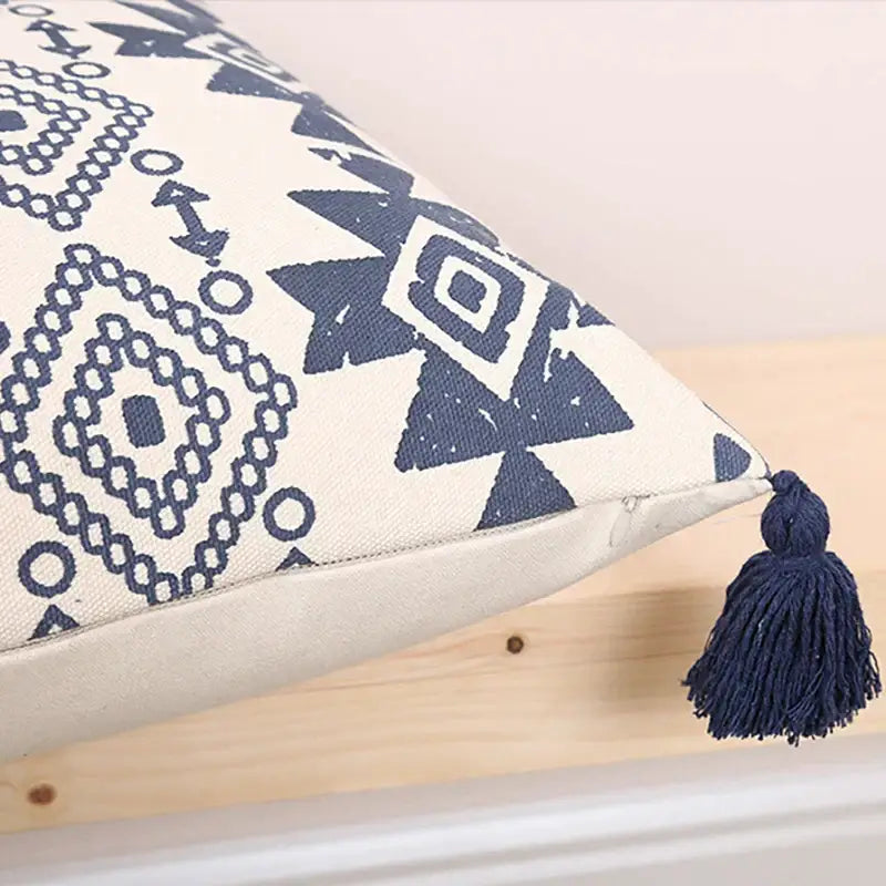 Cream-colored cushion cover with navy blue ethnic geometric printed patterns and matching tassels for living room decorbites