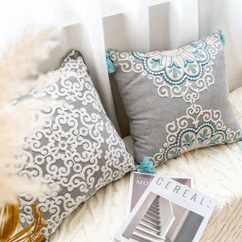 Ethnic gray and white swirl cushion cover with intricate white and teal embroidered patterns and tassels decorbites ethnic pattern