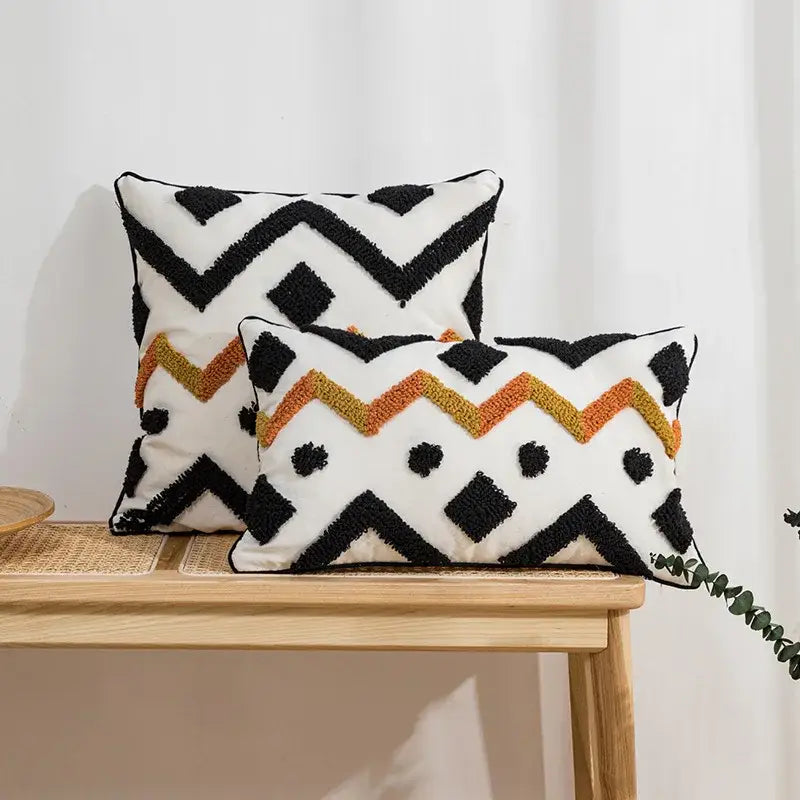 Two rectangular cushion covers in ethnic style black and orange geometric woven fabric with tassel decorbites ethnic style