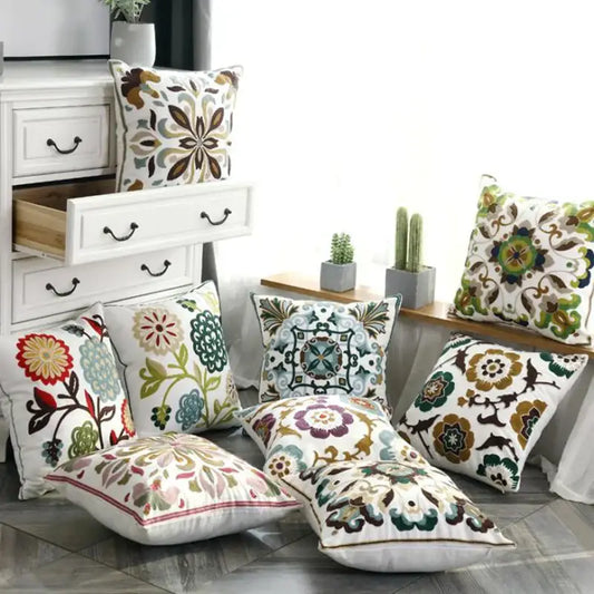 A collection of decorbites ethnic style embroidered pillow covers in vibrant floral and geometric patterns on white canvas