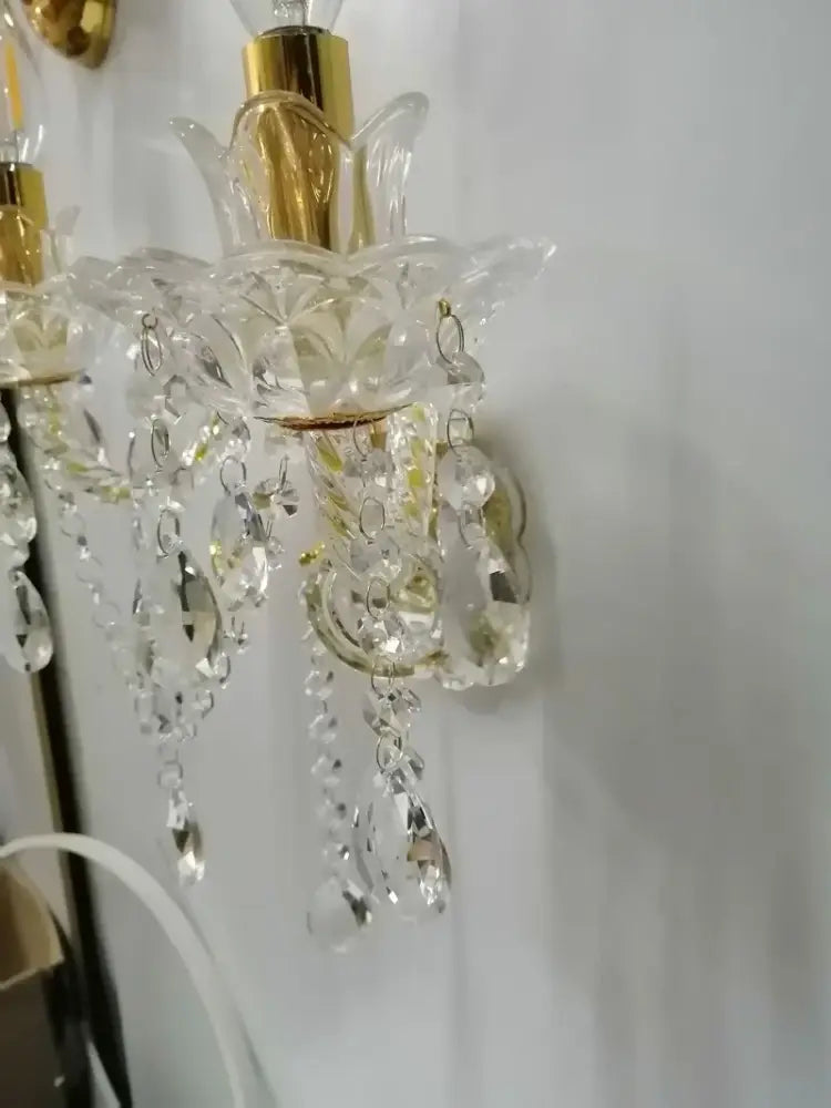 European gold crystal wall lamp with gold-toned metal and dangling teardrop crystals for elegant bedroom decor