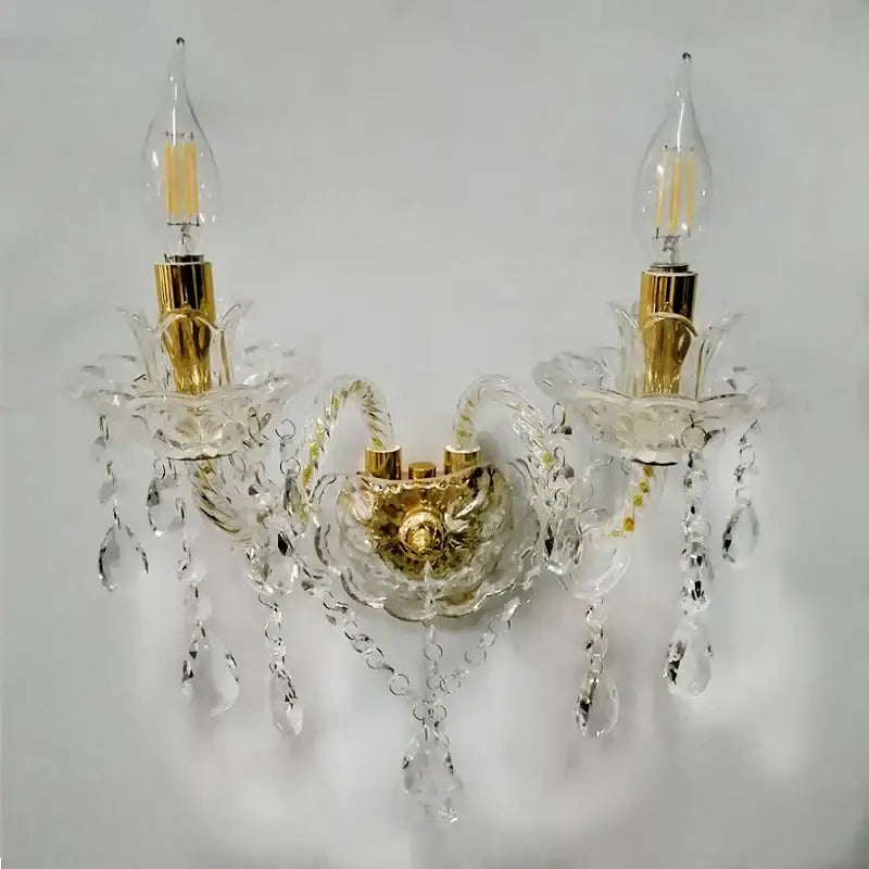 Elegant European gold crystal wall lamp with two candle-style bulbs and dangling teardrop crystals for bedroom use