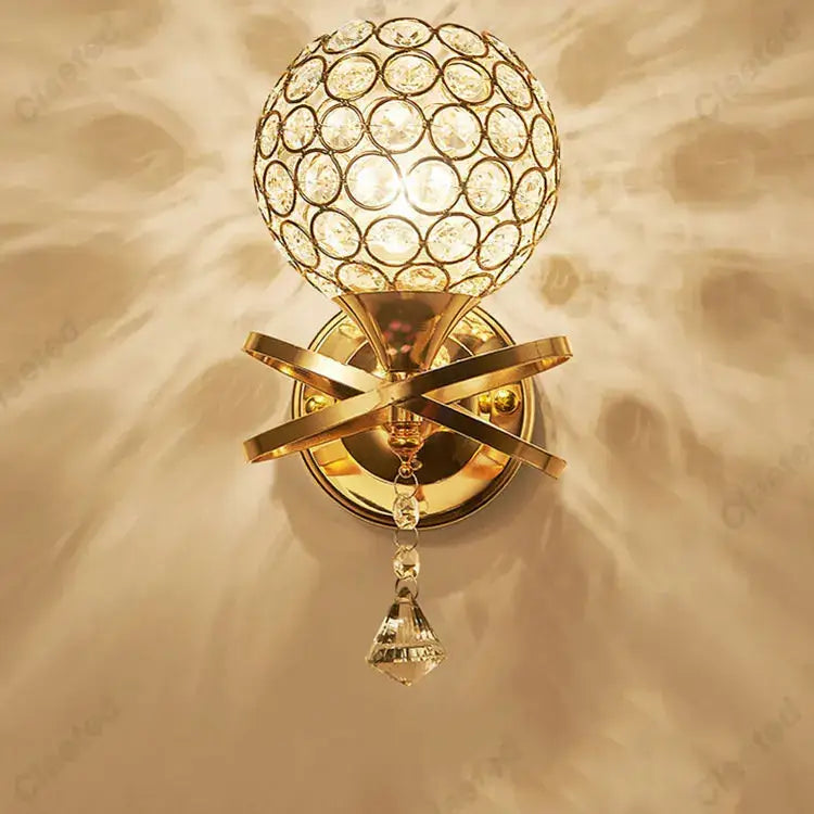 European gold crystal wall light featuring a gold-finished sconce with a spherical globe and faceted crystal pendant