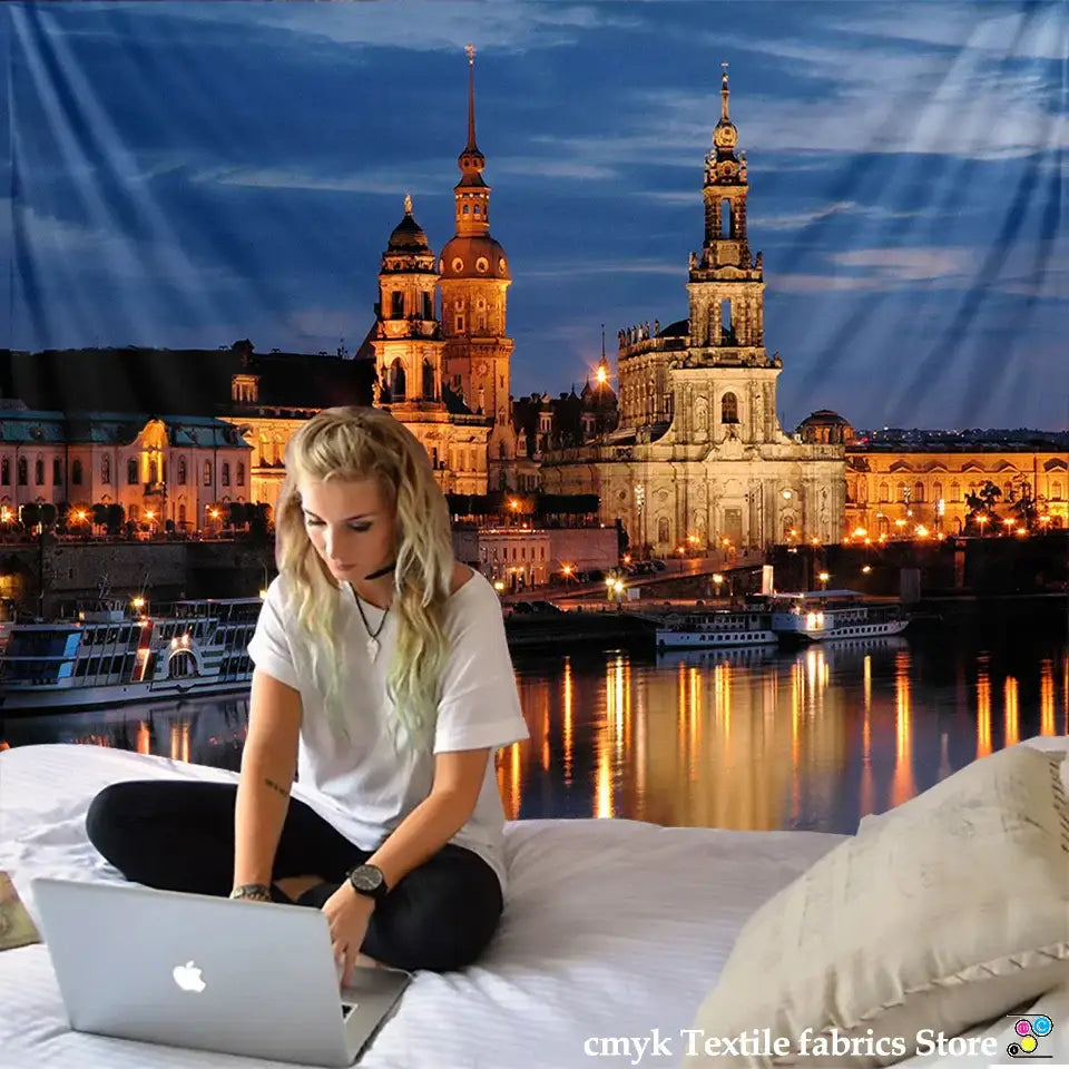 Silver laptop with apple logo placed beside european style city night scene tapestry bedroom wall hanging