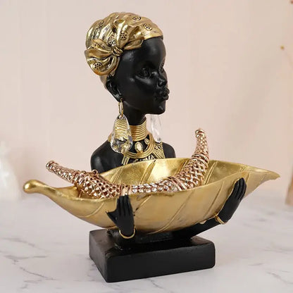 Black african woman resin storage figurine in black and gold holding a leaf-shaped bowl for living room decor