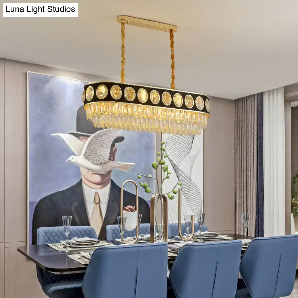 Gold-toned oval pendant light with black frame, faceted crystal droplets, and gold medallions for dining room island