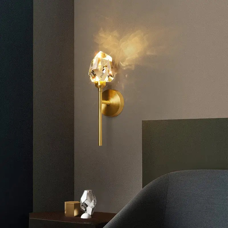 Faceted crystal gold led wall sconce with a gold-toned base and faceted crystal lampshade by Decorbites