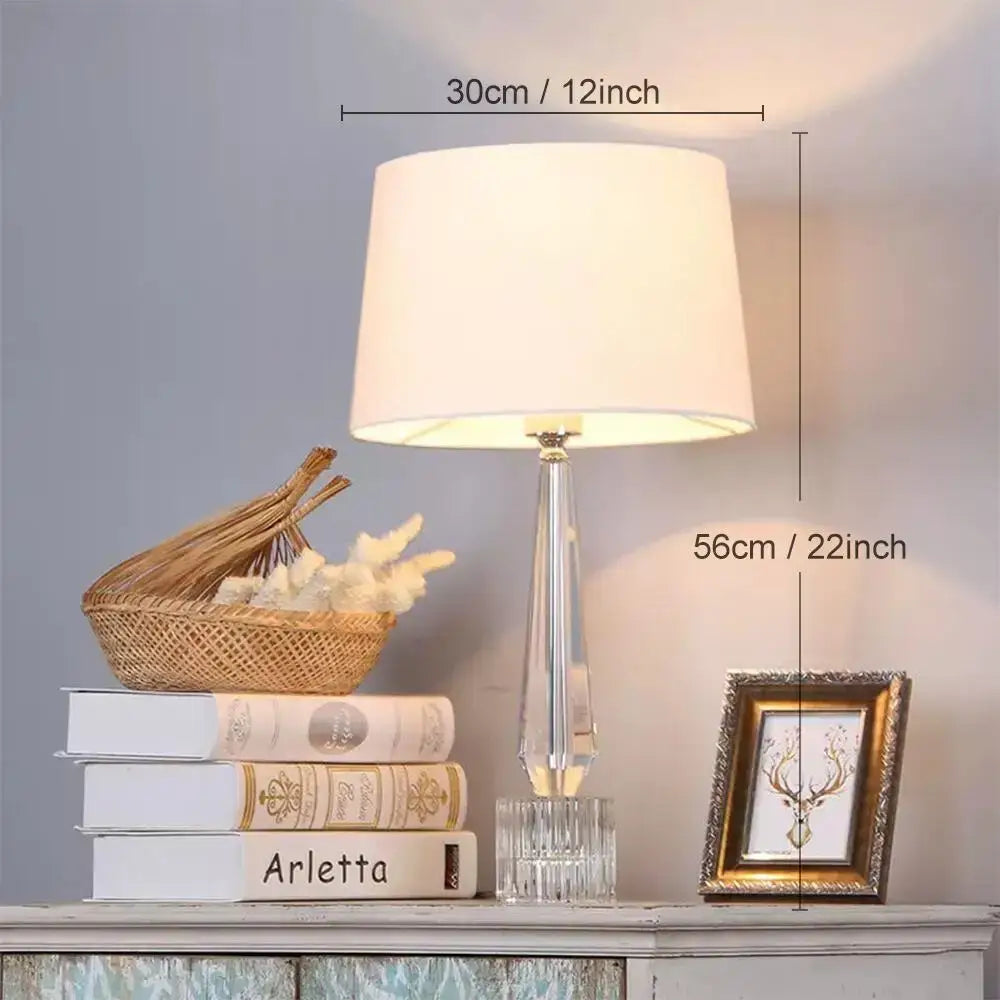 Faceted decorbites crystal table lamp with clear crystal base and off-white fabric shade for bedroom lighting