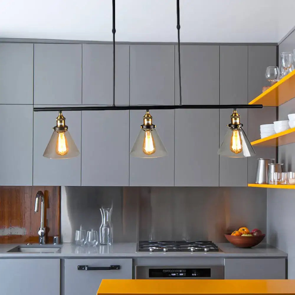 Three clear glass farmhouse cone shade pendant lights with brass fixtures hang above kitchen counter in black finish