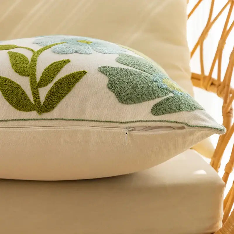 Cream-colored pillow cover with embroidered light blue flowers and olive green leaves for decorbites decorative farmhouse throw