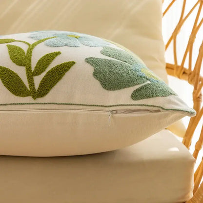 Cream-colored pillow cover with embroidered light blue flowers and olive green leaves for decorbites decorative farmhouse throw