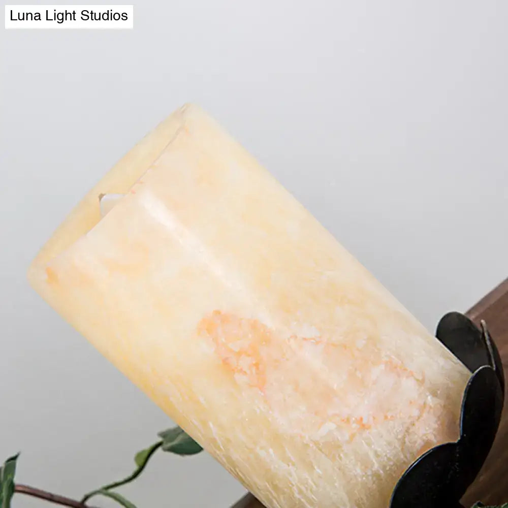 A tall creamy yellow candle with orange veining alongside a farmhouse ivy wooden linear island chandelier