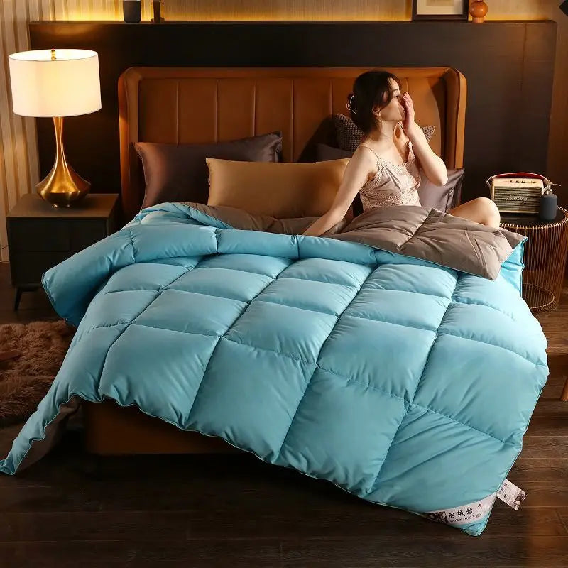 A plush light blue quilted white goose down comforter with soft square stitching for winter bedding use