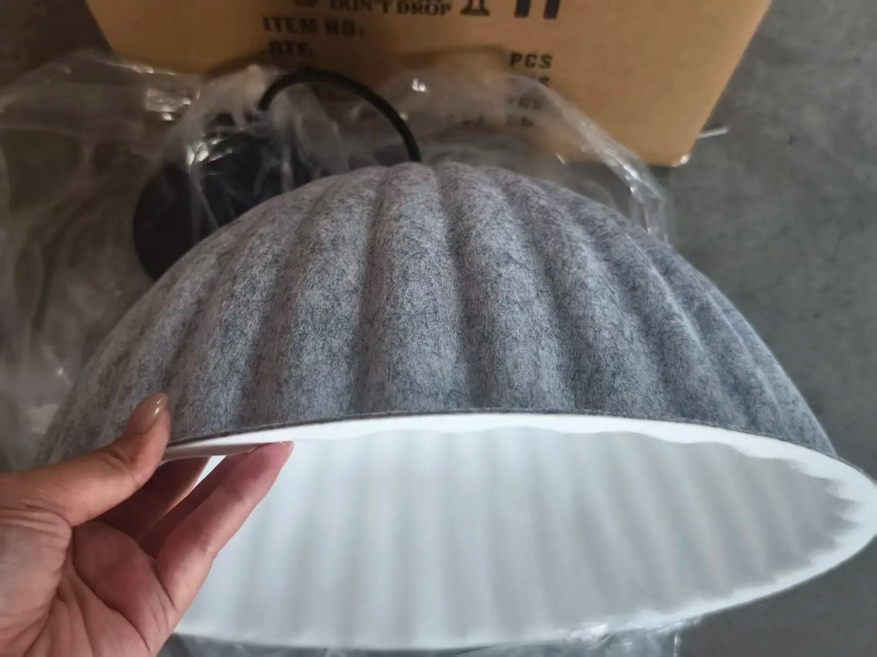 Gray ribbed felt pendant light acoustic with a white interior and fluted edges for office use