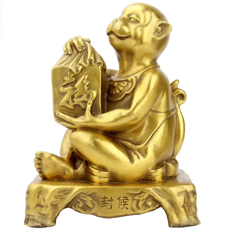 Golden brass copper monkey cornucopia figurine holding a rectangular box with chinese characters on an ornate base