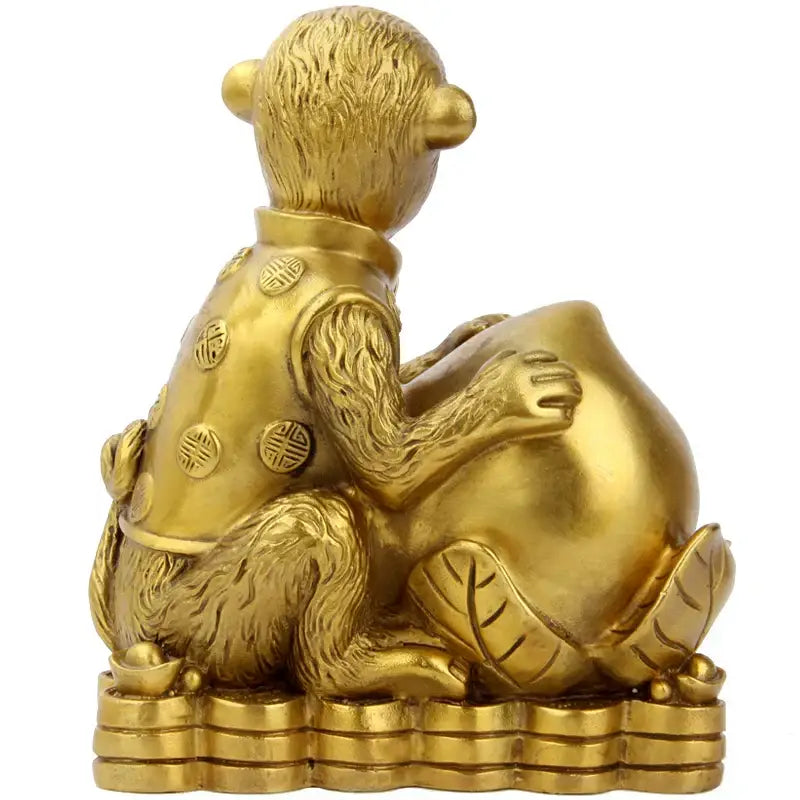 Golden brass copper monkey figurine wearing a vest with chinese characters seated on stacked coins holding a money bag